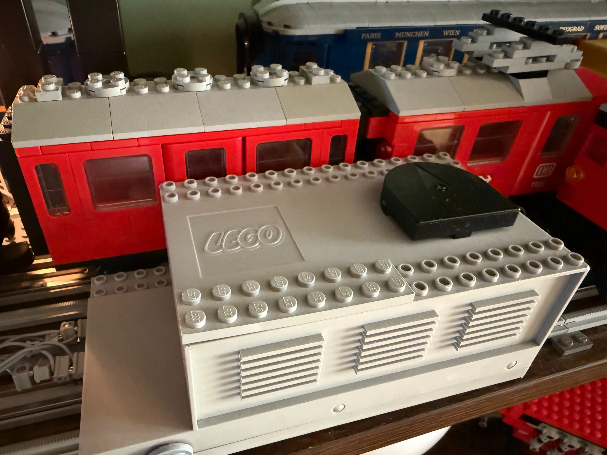 Detail of the LEGO 12V transformer beside a red Grey Era train